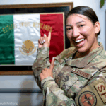 Soldado de origen mexicano sonríe a la cámara, detrás se observa una bandera de México / Foto U.S Air Force